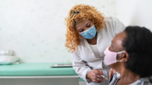 A female presenting person receives a vaccine shot from a healthcare provider