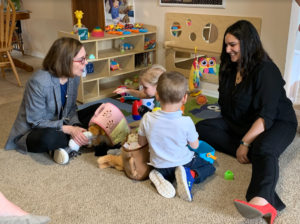 Photo: Governor Kate Brown sits on the floor with the Early Learning Division Director Alyssa Chatterjee with two young children at a Child Care provider's in-home daycare.