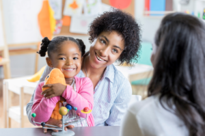 A young mother and her daughter have a conversation with a preschool teacher