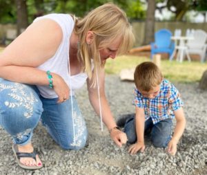 A blonde woman, Dr. Velvet Cooley, counts rocks with a young boy in the playground. Dr. Cooley has researched the mental and physical health benefits to young children learning outdoors.