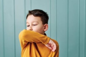 A child covers his cough with his elbow